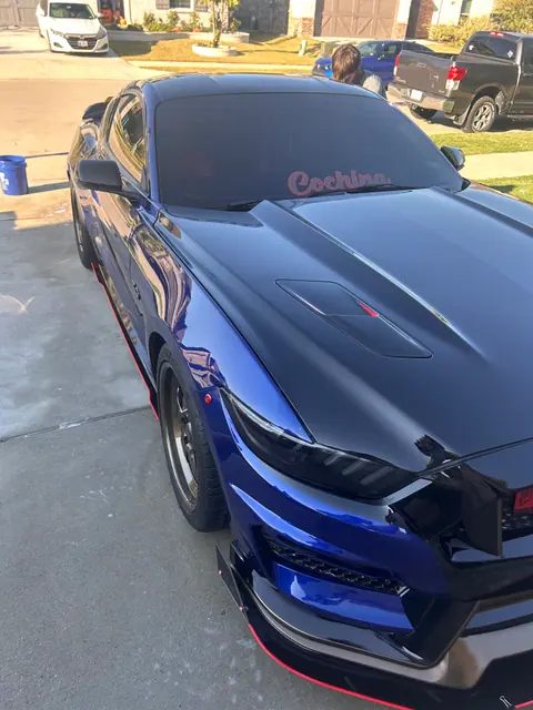 Close view of a glossy blue Ford Mustang hood and headlight after detailing